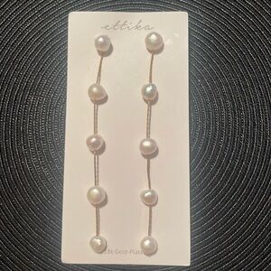 Ettika freshwater pearls long linear drop earrings plated in 18-karat gold.